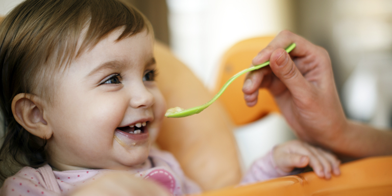 Un bambino sorridente riceve un cucchiaio di porridge