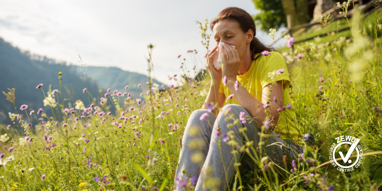 Una donna siede in un campo e soffre di allergia ai pollini.