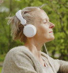 Eine Frau sitzt auf einer Parkbank mit geschlossenen Augen und geniesst das Wetter.